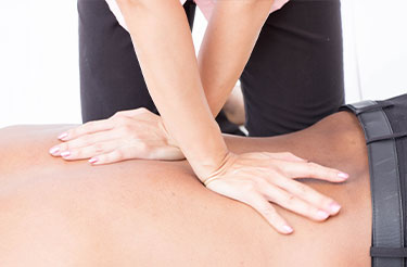Physiotherapist performing spinal mobilization technique on patient's back